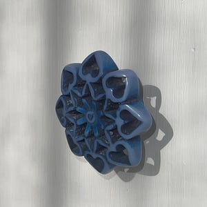 May include: A blue ceramic door knob with a decorative design of hearts and a starburst in the center.