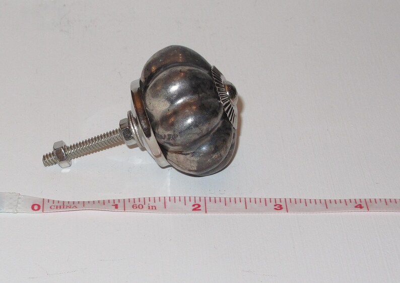 Puede incluir: Pomo de armario en forma de calabaza de color plateado con un tornillo y una tuerca. El pomo tiene un di&aacute;metro de aproximadamente 2,5 cm.