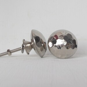 May include: Two silver hammered metal cabinet knobs with a screw and nut.
