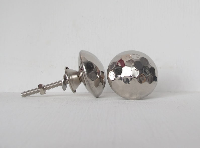 May include: Two silver hammered metal cabinet knobs with a screw and nut.