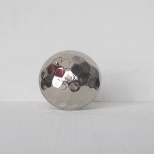 May include: A silver hammered metal sphere with a textured surface.