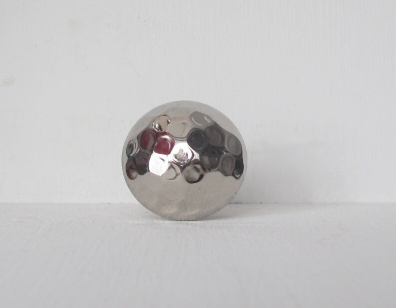 May include: A silver hammered metal sphere with a textured surface.