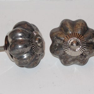 Puede incluir: Dos pomos de armario de metal plateado con un dise&ntilde;o texturizado en forma de calabaza. Cada pomo tiene un centro de metal plateado con un dise&ntilde;o circular en relieve.