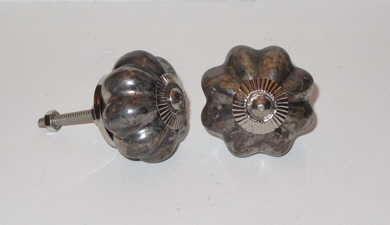 Puede incluir: Dos pomos de armario de metal plateado con un dise&ntilde;o texturizado en forma de calabaza. Cada pomo tiene un centro de metal plateado con un dise&ntilde;o circular en relieve.