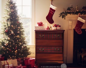 Pode incluir: Uma cómoda de madeira com três gavetas decorada com papel de contacto xadrez vermelho e preto. A cómoda está decorada para o Natal com uma árvore de Natal, presentes e meias.