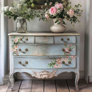 Peut inclure: Une commode bleu clair avec des décalcomanies florales et des poignées dorées. La commode a quatre tiroirs et repose sur quatre pieds. La commode est décorée de fleurs dans un vase.