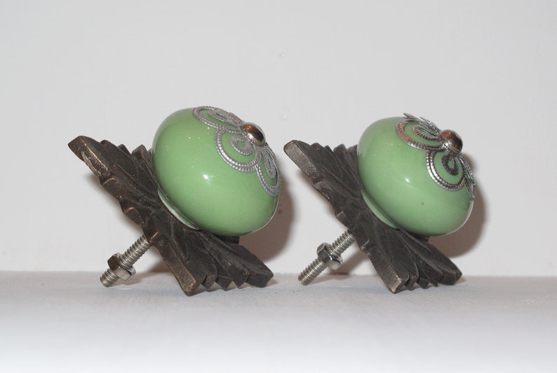 Peut inclure: Deux boutons de cabinet en c&eacute;ramique verte avec des accents argent&eacute;s et une base en bronze d&eacute;corative.