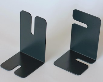 May include: Two dark teal metal bookends. Each bookend has a right-angled base with a curved cutout and a vertical support with a U-shaped cutout. The bookends are designed to hold books upright on a shelf.