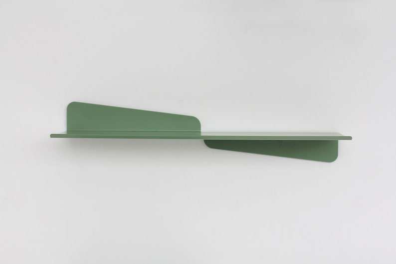 May include: A modern, minimalist wall shelf in a muted green color. The shelf has a long, horizontal surface with two angled supports, creating a unique and contemporary design. The shelf is made of metal and is mounted on a white wall.