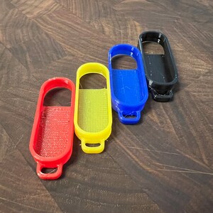 May include: Four colorful bottle openers in red, yellow, blue, and black. Each opener has a unique design and a small loop for attaching to a keychain.