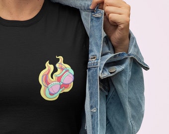 Puede incluir: Camiseta negra con un gráfico colorido de un sujetador en llamas.