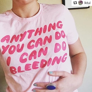 Puede incluir: Camiseta rosa con el texto "Anything you can do I can do bleeding" en letras rosas.