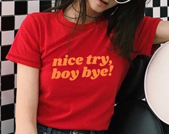 Puede incluir: Camiseta roja de manga corta con el texto "nice try, boy bye!" en letras naranjas.