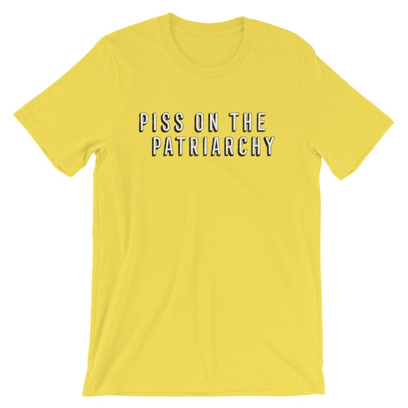 Puede incluir: Camiseta amarilla de manga corta con el texto "PISS ON THE PATRIARCHY" impreso en negro.