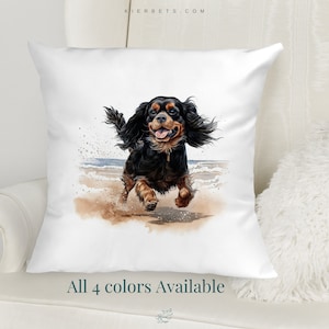 Puede incluir: Una almohada blanca con una ilustración de acuarela de un Cavalier King Charles Spaniel negro y marrón corriendo por una playa. El texto "All 4 colors Available" está impreso debajo de la imagen.