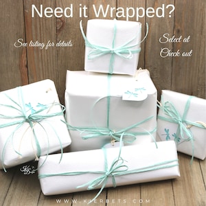 Op de afbeelding: Vijf witte cadeaudozen verpakt in wit papier met een lichtblauw lint en een libellenontwerp. De dozen zijn op elkaar gestapeld op een houten oppervlak. De tekst "Need it Wrapped?" staat bovenaan de afbeelding. De tekst "See listing for details" staat links in de afbeelding. De tekst "Select at Check out" staat rechts in de afbeelding.