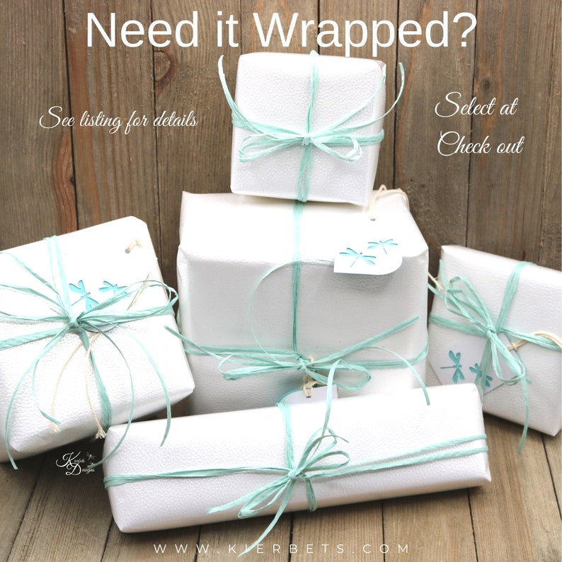 Op de afbeelding: Vijf witte cadeaudozen verpakt in wit papier met een lichtblauw lint en een libellenontwerp. De dozen zijn op elkaar gestapeld op een houten oppervlak. De tekst "Need it Wrapped?" staat bovenaan de afbeelding. De tekst "See listing for details" staat links in de afbeelding. De tekst "Select at Check out" staat rechts in de afbeelding.