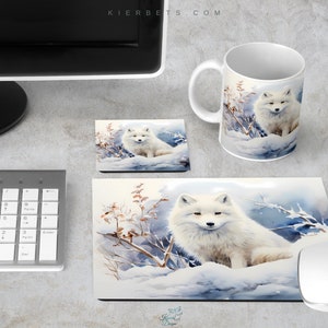 May include: A white ceramic mug with a watercolor illustration of an arctic fox in a snowy landscape. The mug is on a white surface next to a computer mouse, a keyboard, and a mouse pad with the same illustration. The mouse pad is larger than the mug and has a white border. The mug has a handle on the right side. The illustration on the mug and mouse pad is a watercolor painting of an arctic fox in a snowy landscape. The fox is white with black eyes and a black nose. The fox is sitting in the snow with its head turned to the right. The background of the illustration is a snowy landscape with trees and bushes. The illustration is surrounded by a white border.
