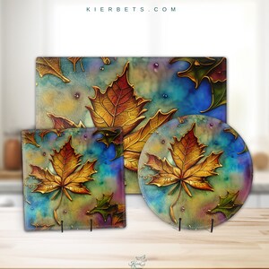 Könnte beinhalten: Set aus drei Glas-Schneidebrettern mit einem Aquarell-Design aus goldenen Ahornblättern auf blauem und grünem Hintergrund. Die Bretter sind in verschiedenen Größen und Formen und alle auf einer Holzoberfläche.