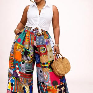 May include: Wide-leg patchwork pants in vibrant colors, featuring a mix of geometric and abstract patterns. The pants are paired with a white sleeveless top and a round woven handbag. Red shoes complete the look.
