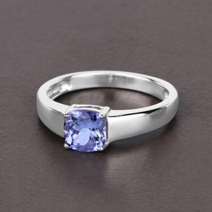 May include: A silver ring with a cushion-cut blue gemstone.