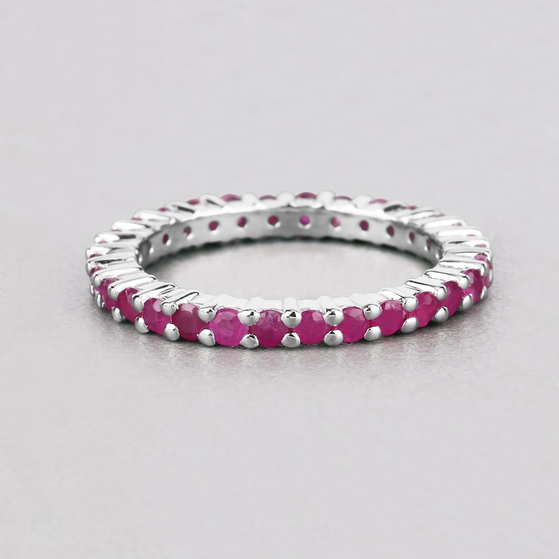 May include: A silver band ring with a row of small, round, pink gemstones.