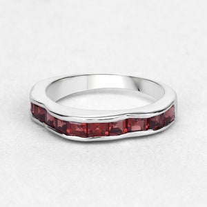 May include: A silver band ring with a row of red square-shaped gemstones.