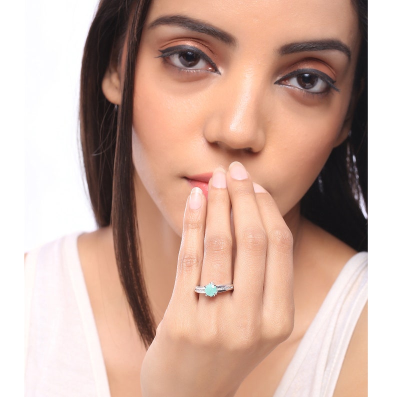 May include: A silver ring with a light blue gemstone. The ring has a simple design with a thin band and a small, round stone.
