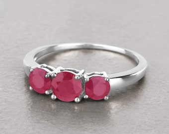 Puede incluir: Un anillo de plata con tres piedras preciosas redondas de color rojo engastadas en fila.