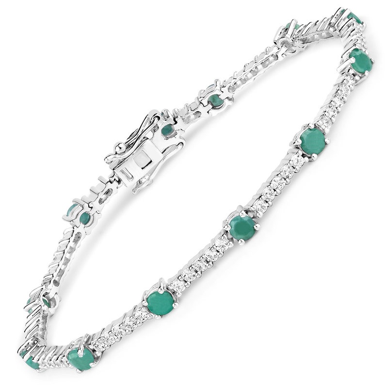 May include: A silver bracelet featuring a line of green gemstones and smaller clear gemstones. The bracelet has a lobster claw clasp.