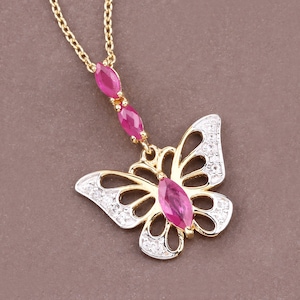May include: A gold butterfly pendant necklace with red ruby stones and clear cubic zirconia accents.