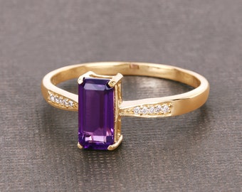May include: A gold ring featuring a purple amethyst gemstone and small clear diamonds set in the band.