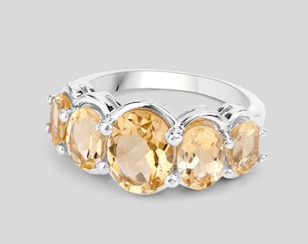 May include: A silver ring with five oval-shaped topaz gemstones. The ring is set in a prong setting and has a polished finish.