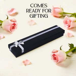 May include: A black velvet gift box with a silver ribbon and bow. The box is ready for gifting and has the text "COMES READY FOR GIFTING" printed on a white background.