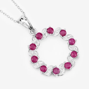 May include: A silver necklace with a pendant featuring a circle of red rubies and white diamonds.