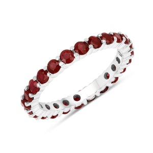 May include: A silver eternity band ring with a row of red ruby gemstones.