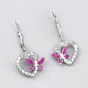 May include: Silver dangle earrings with a heart-shaped design featuring a butterfly with pink gemstones. The earrings have a lever back closure.