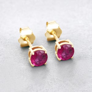 May include: A pair of gold stud earrings with round pink gemstones.