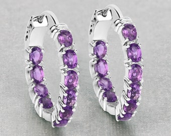 May include: A pair of silver hoop earrings with a row of purple amethyst gemstones around the hoop.