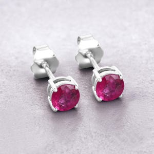 May include: A pair of silver stud earrings with round pink gemstones.