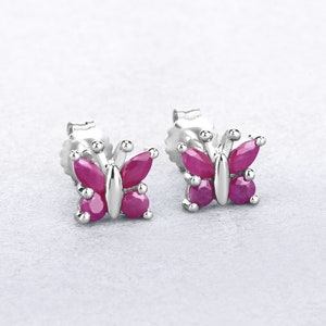 May include: A pair of silver butterfly earrings with pink gemstones. The earrings are small and delicate, perfect for everyday wear.