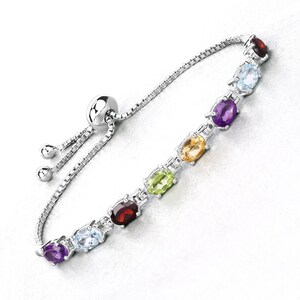 May include: A silver bracelet with an adjustable sliding clasp features a row of oval-shaped gemstones in various colors, including amethyst, sky blue topaz, peridot, citrine, and garnet.