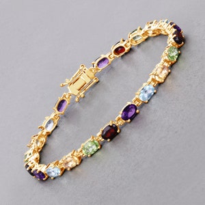 May include: A gold bracelet with oval-shaped gemstones in various colors, including amethyst, peridot, citrine, aquamarine, and garnet.