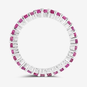May include: A silver eternity band ring with pink gemstones set in a continuous circle.