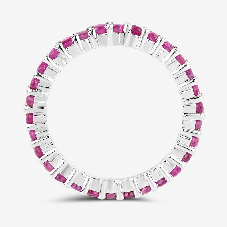 May include: A silver eternity band ring with pink gemstones set in a continuous circle.