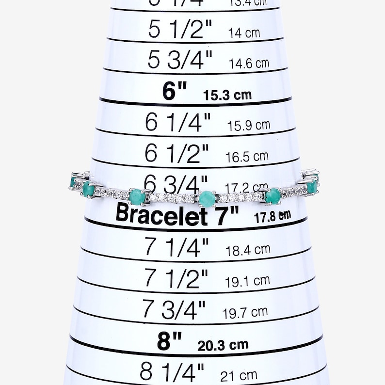 May include: A silver bracelet with green gemstones and white diamonds. The bracelet is measured on a sizing chart and is 7 inches in length.
