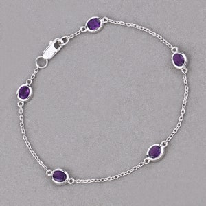 Puede incluir: Un brazalete de cadena de plata con cinco piedras de amatista ovaladas.