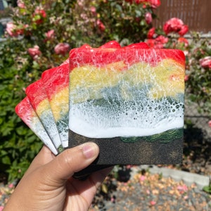 May include: Set of four colorful coasters with a layered design. The coasters feature a red, yellow, green, and white color scheme with a black base. The coasters are made of resin and have a glossy finish.