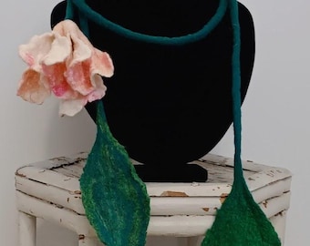 Può includere: Una collana in feltro turchese con un fiore in feltro rosa e due foglie in feltro verde.