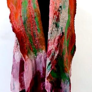 May include: A long, textured scarf featuring a vibrant blend of orange, green, and deep red felted wool fibers. The lower sections transition into a lighter, semi-sheer pink fabric with mottled, watercolor-like patterns and uneven, frayed edges.